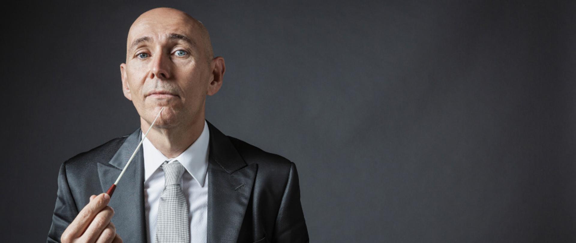 Zdjęcie na czarnym tle przedstawiącym dyrygenta Enrico Onofri z European Union Baroque Orchestra.