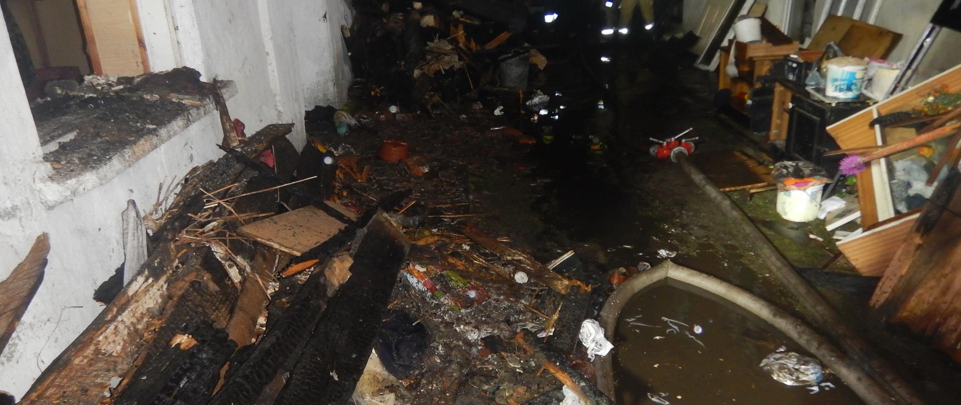 Zdjęcie przedstawia spalone mienie, które wyniesiono w toku akcji ratowniczo - gasniczej