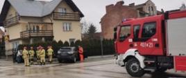 Zdjęcie przedstawia strażaków prowadzących działania ratownicze podczas wypadku drogowego w tle samochód pożarniczy