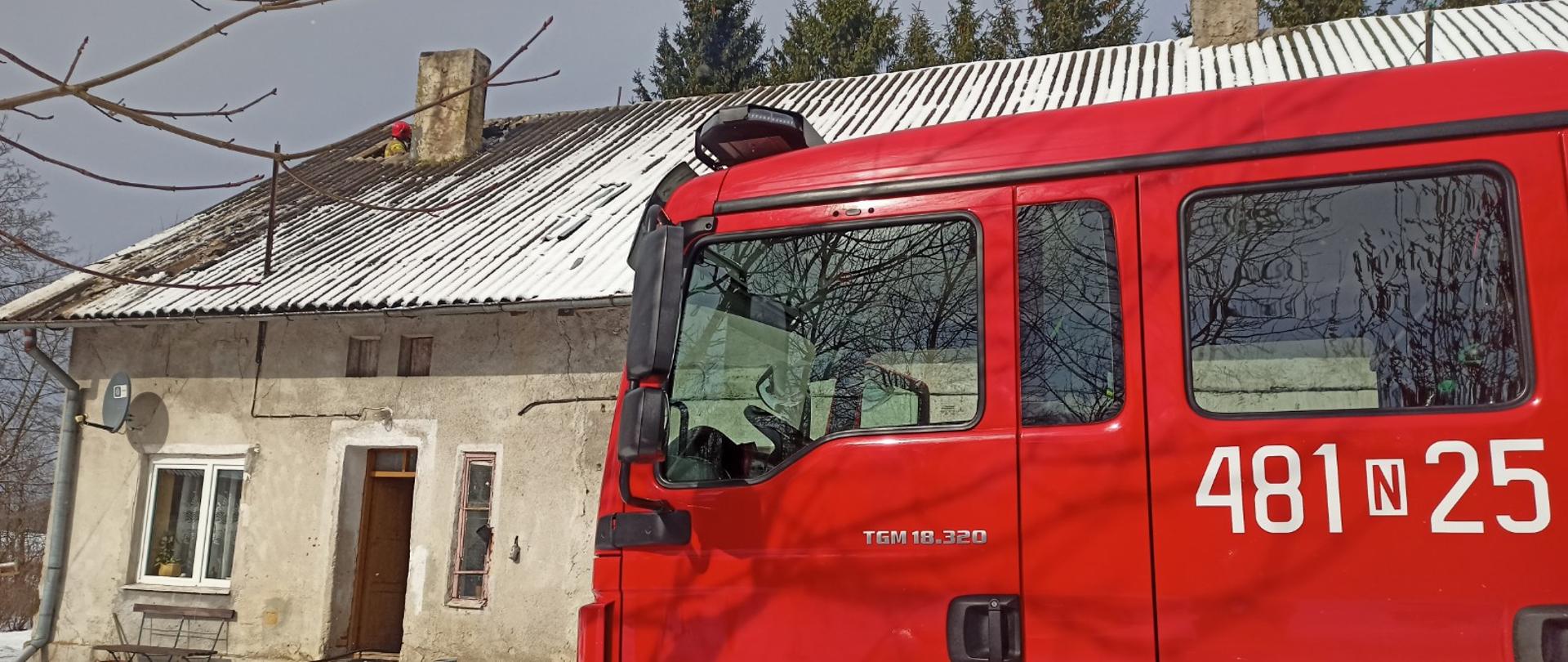 Zdjęcie przedstawia samochód pożarniczy na tle zagrożonego budynku podczas prowadzonych działań rozbiórkowych 