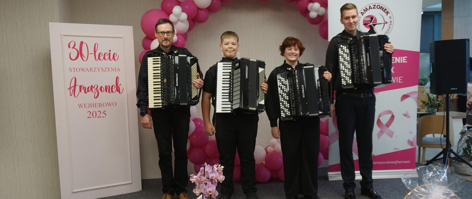 Na estradzie pozuje wraz z akordeonami trójka uczniów oraz nauczyciel Ryszard Borysionek. W tle różowo-białe balony i baner z napisem "XXX lecie Stowarzyszenia Amazonek, Wejherowo 2025"