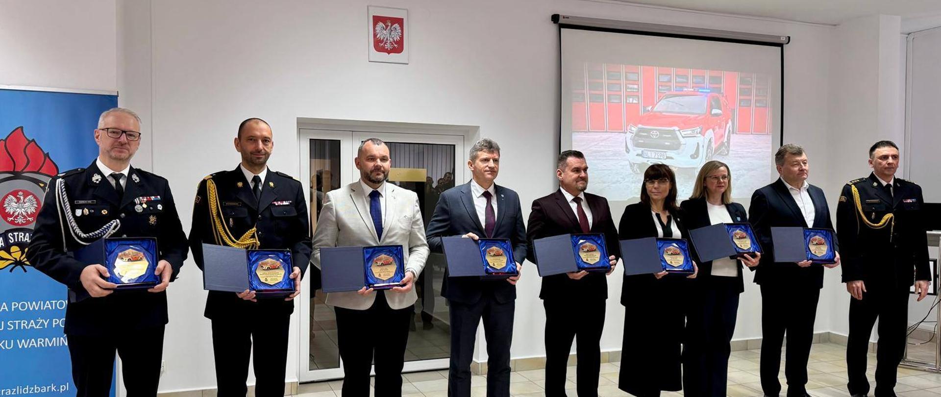 grupa elegancko ubranych ludzi trzyma wyróżnienia pozując do zdjęcia 