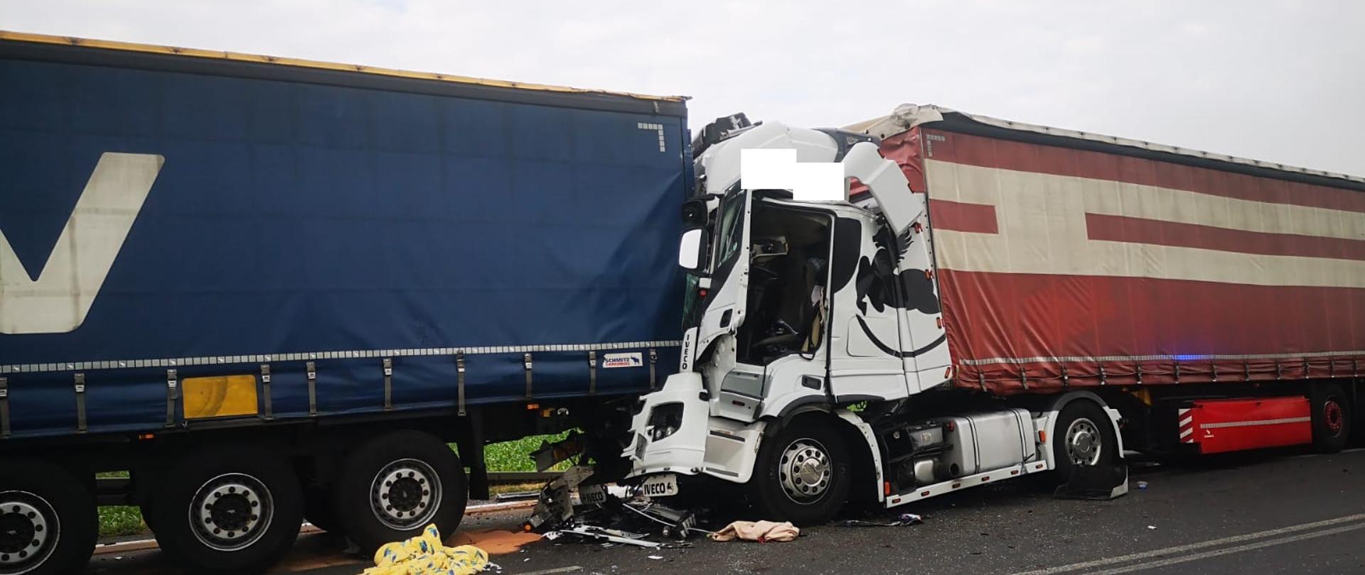 Widać samochód ciężarowy z mocno uszkodzoną kabiną, który uderzył w naczepę poprzedzającego pojazdu