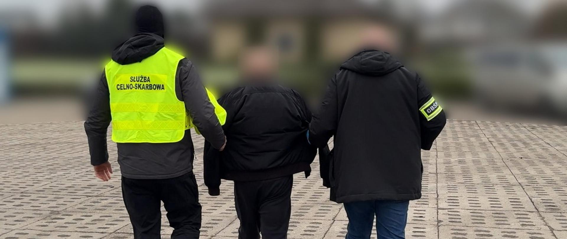 Funkcjonariusze KAS i CBŚP prowadzą zatrzymanego mężczyznę