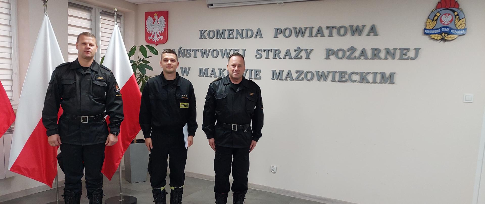 Trzech funkcjonariuszy stoi w szeregu na świetlicy Komendy. 