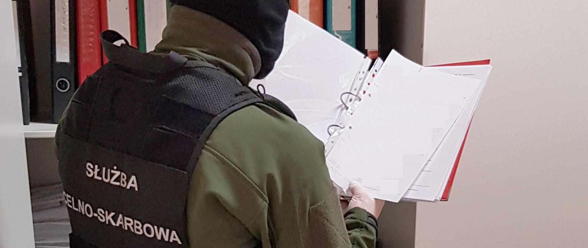 Funkcjonariusz Służby Celno-Skarbowej przeglądający faktury.