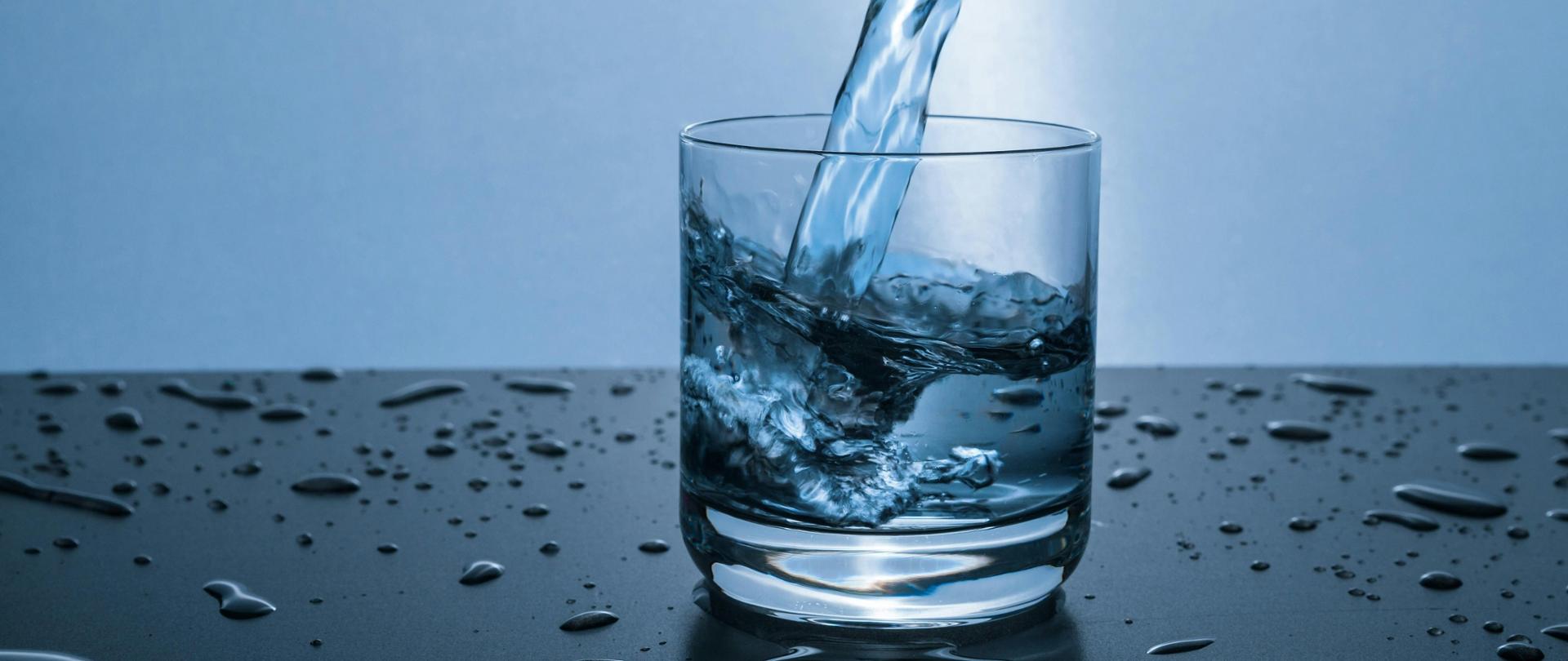 Szklanka do której z góry leje się strumień wody