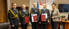 Wspólne zdjęcie grupowe nagrodzonych funkcjonariuszy, Wojewody Opolskiego i Opolskiego Komendanta Wojewódzkiego PSP. Strażacy w umundurowaniu galowym.