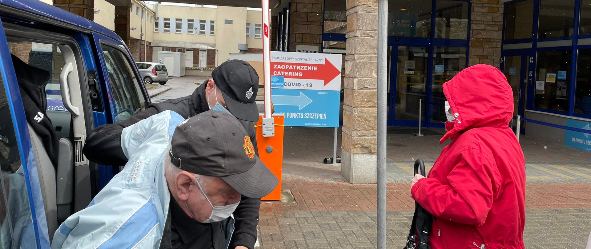 Druh OSP Sopot pomaga starszemu mężczyźnie wyjść busa i dotrzeć do szpitala na szczepienie przeciw COVID