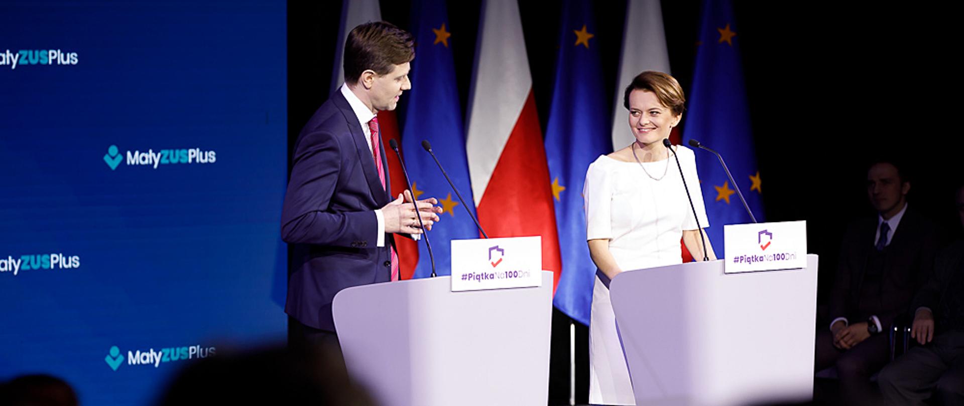 Jadwiga Emilewicz w towarzystwie przedsiębiorcy, stoją za mównicami, za nimi tło z logiem "Mały ZUS plus"