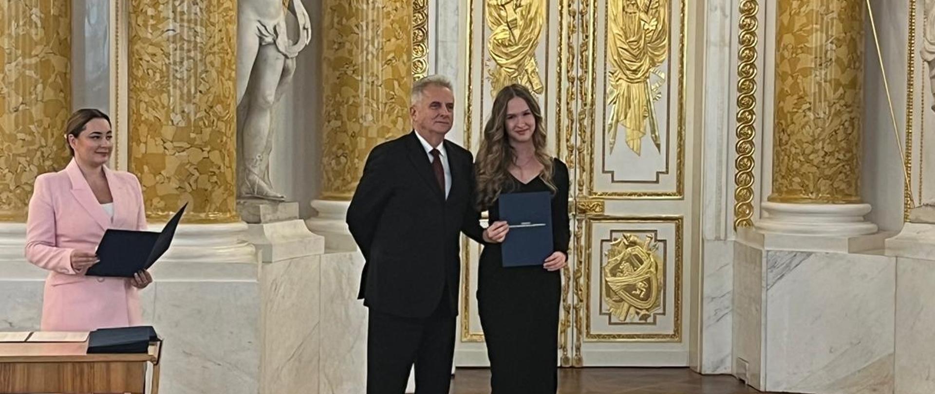 Foto- uczennica Amelia Szmidt odbiera stypendium MKiDN. Zdjęcie z sali Zamku Królewskiego w Warszawie.