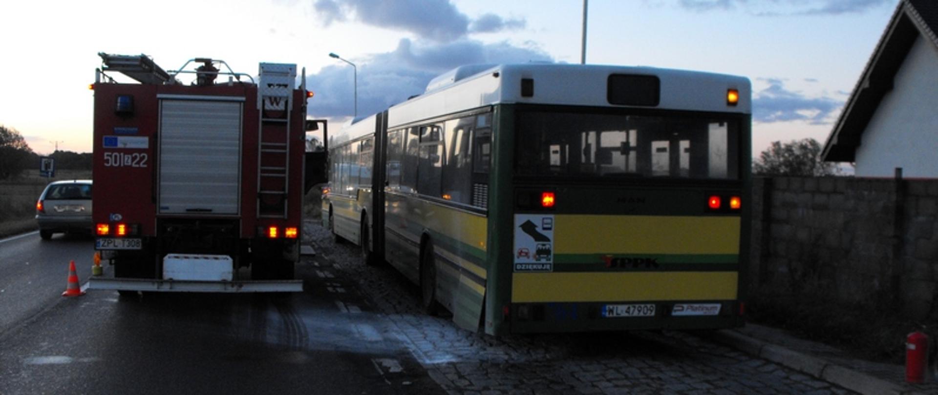 Zdjęcie przedstawia samochód pożarniczy obok autobusu