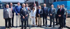 Uczestnicy konferencji prasowej stoją przed terminalem odpraw na przejściu granicznym.