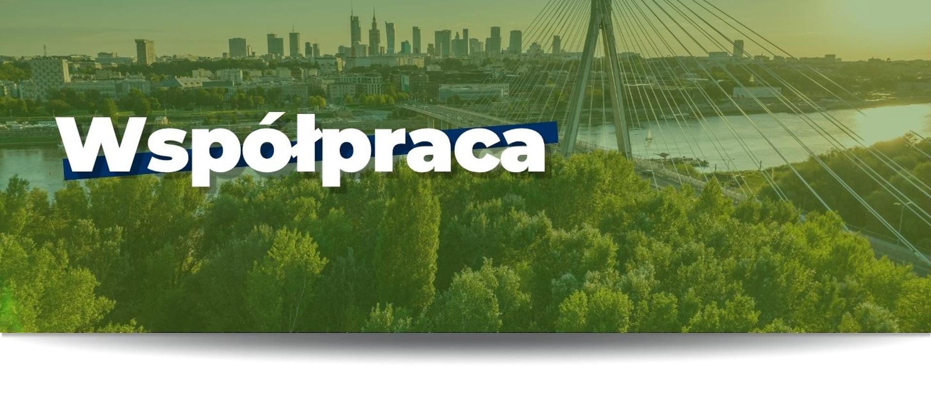 Na grafice widnieje biały napis "Współpraca", w tle jest pokazane zdjęcie Warszawy. Na pierwszym planie widać zielone drzewa, rzekę Wisłę oraz Most Świętokrzyski. W oddali widać wysokie budynki, w tym Pałac Kultury i Nauki.