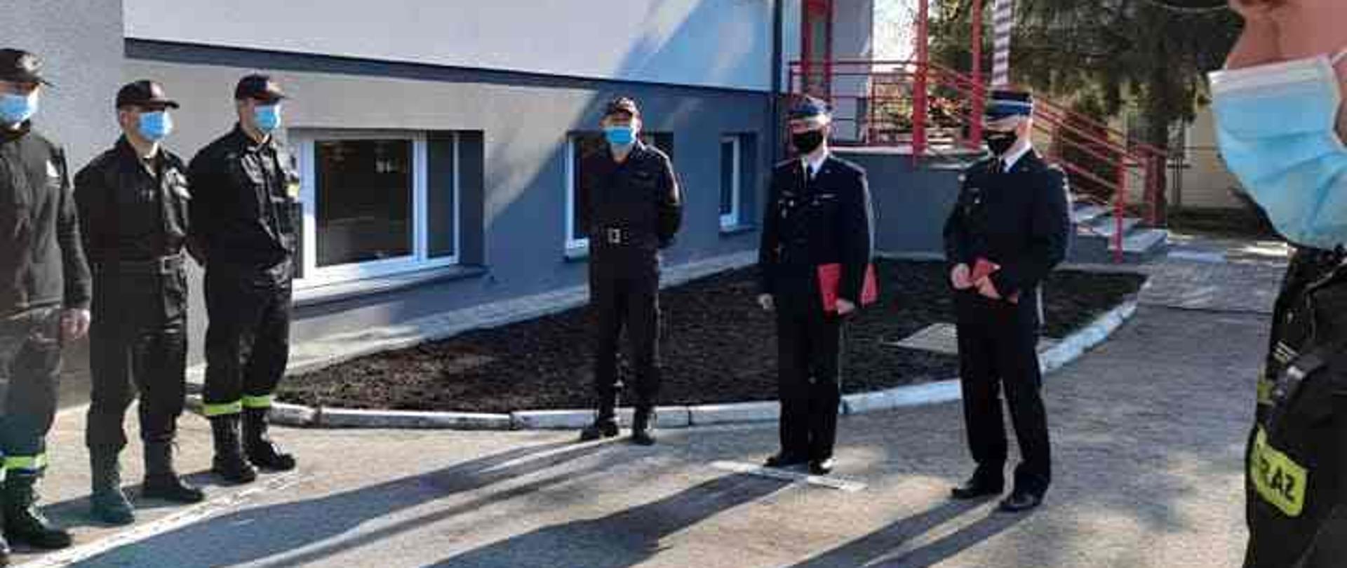 Strażacy stojący przed strażnicą,