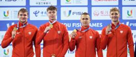 Czterech mężczyzn w czerwonych sportowych bluzach pokazuje medale na wstążkach.
