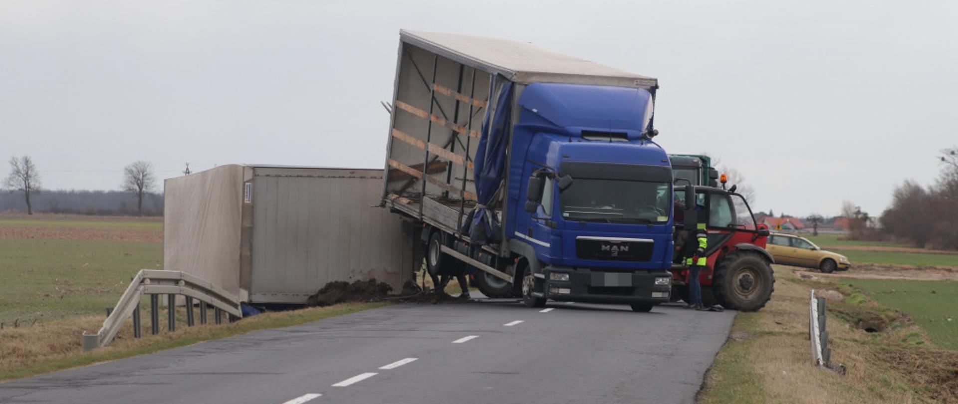 Na zdjęciu znajduje się samochód ciężarowy, który jest częściowo przewrócony.