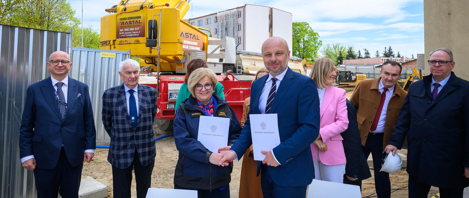 Zdjęcie przedstawia uczestników podpisania umowy na placu budowy