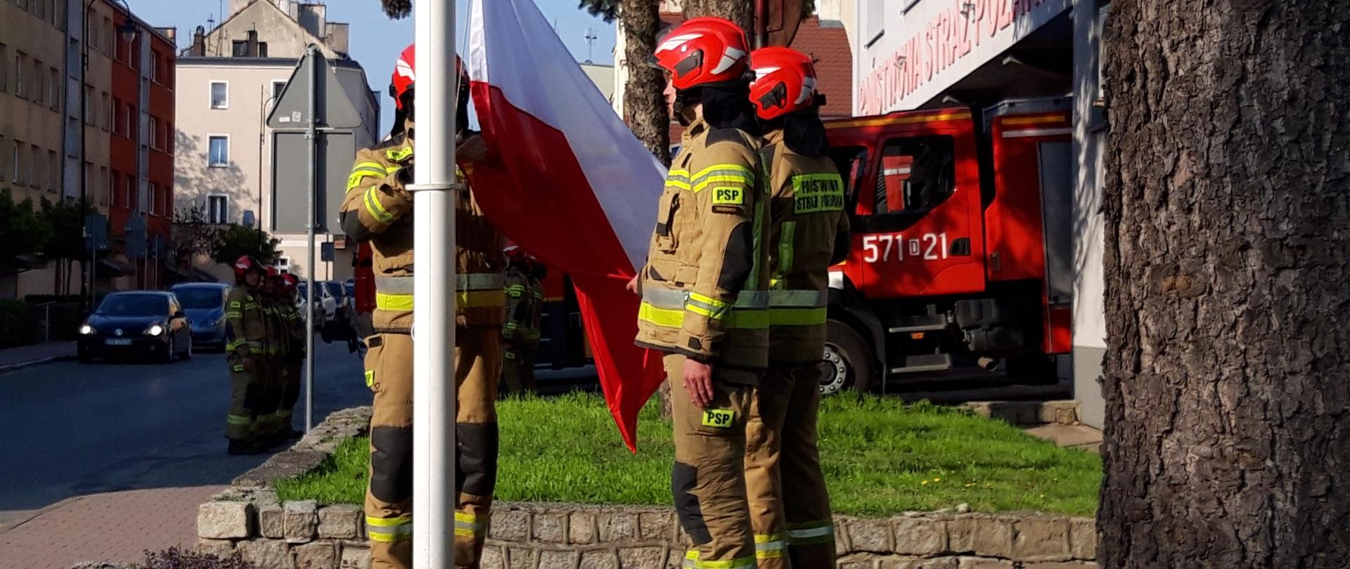Strażacy wciągają flagę na maszt
