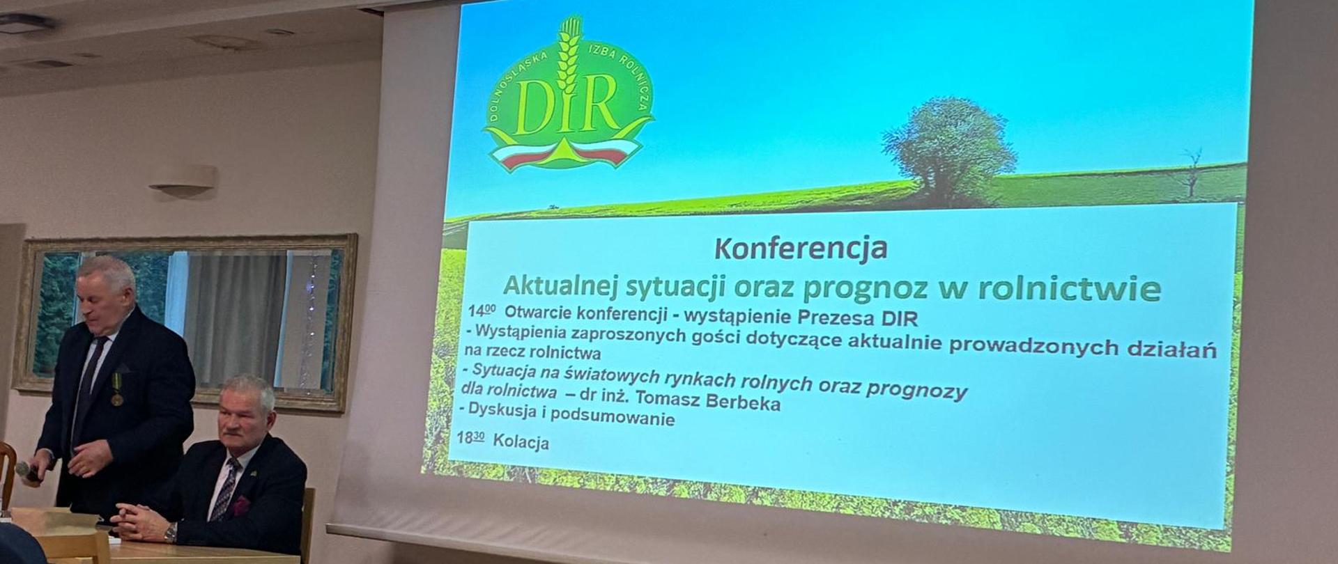 Wykładowcy prezentujący slajdy w prezentacji.