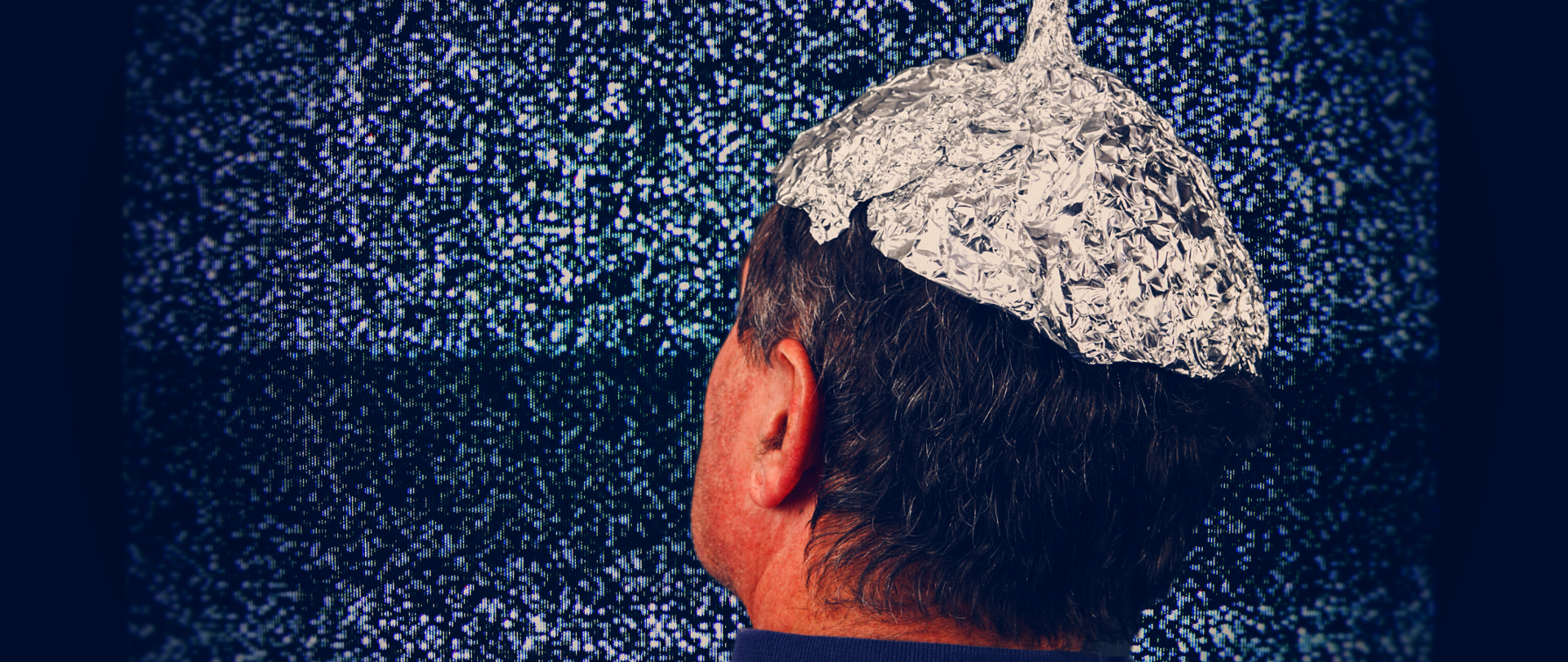 Głowa mężczyzny w czapce z folii aluminiowej. W tle ekran telewizora.