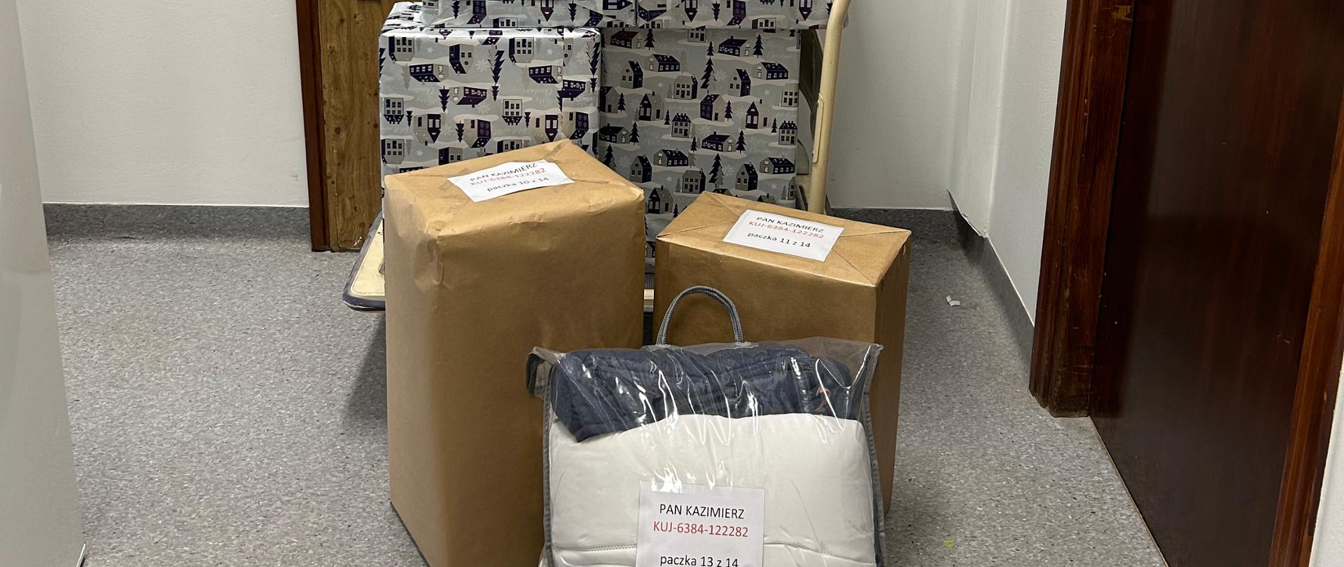 Paczki z prezentami - kartony - ustawione w stos na korytarzu 