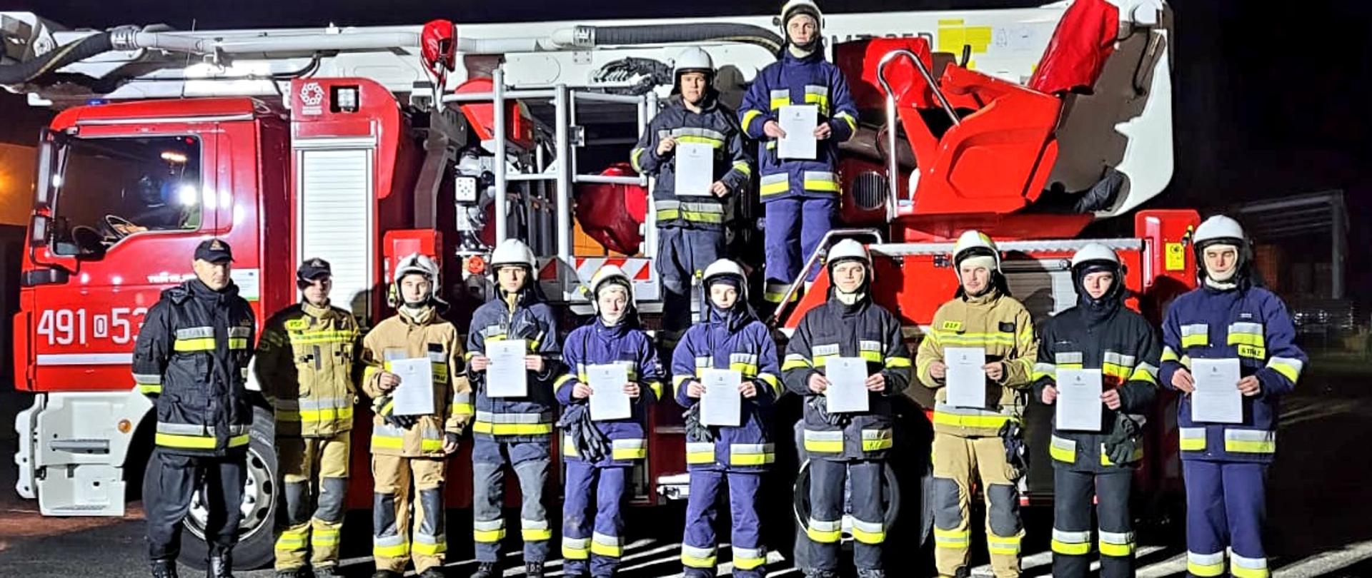 Zdjęcie przedstawia strażaków OSP na tle podnośnika SHD