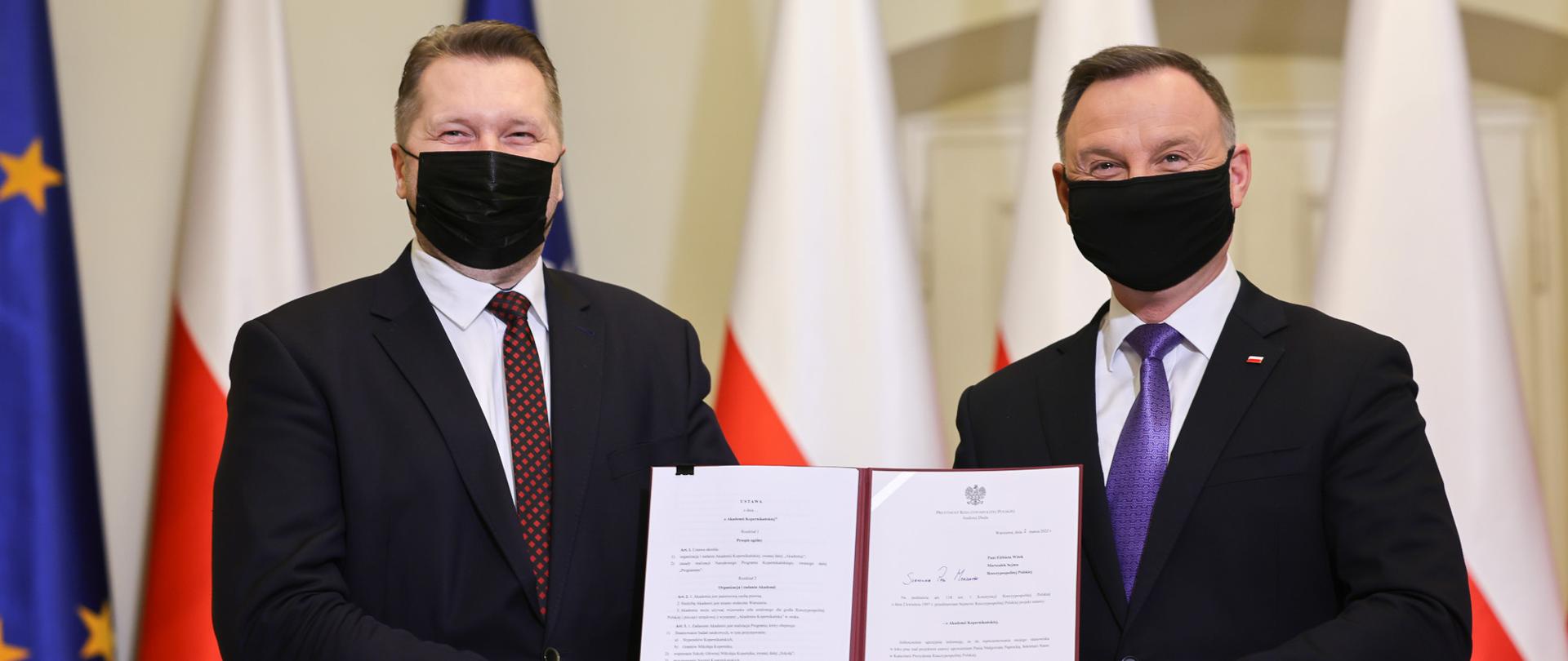 Minister Przemysław Czarnek i prezydent RP Andrzej Duda trzymają razem podpisany dokument.