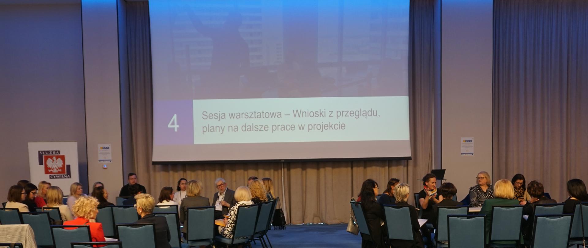 Warsztaty podsumowujące projekt Procedury Bez Barier - dwie grupy uczestników siedzą dookoła stołów