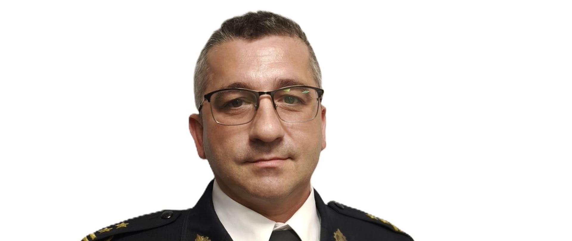 Mężczyzna w średnim wieku w mundurze galowym państwowej straży pożarnej. Patrzy na wprost, widoczny od pasa w górę. Nosi okulary.