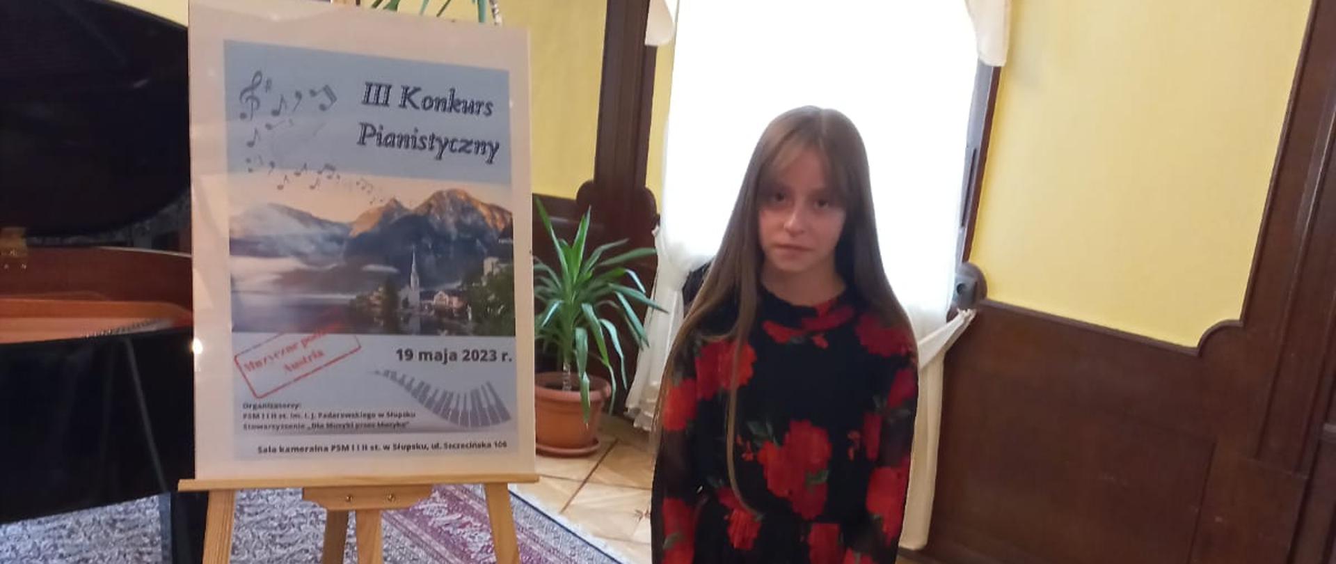 Uczennica Marta Melzacka stoi przy afiszu Konkursu Pianistycznego w Słupsku 