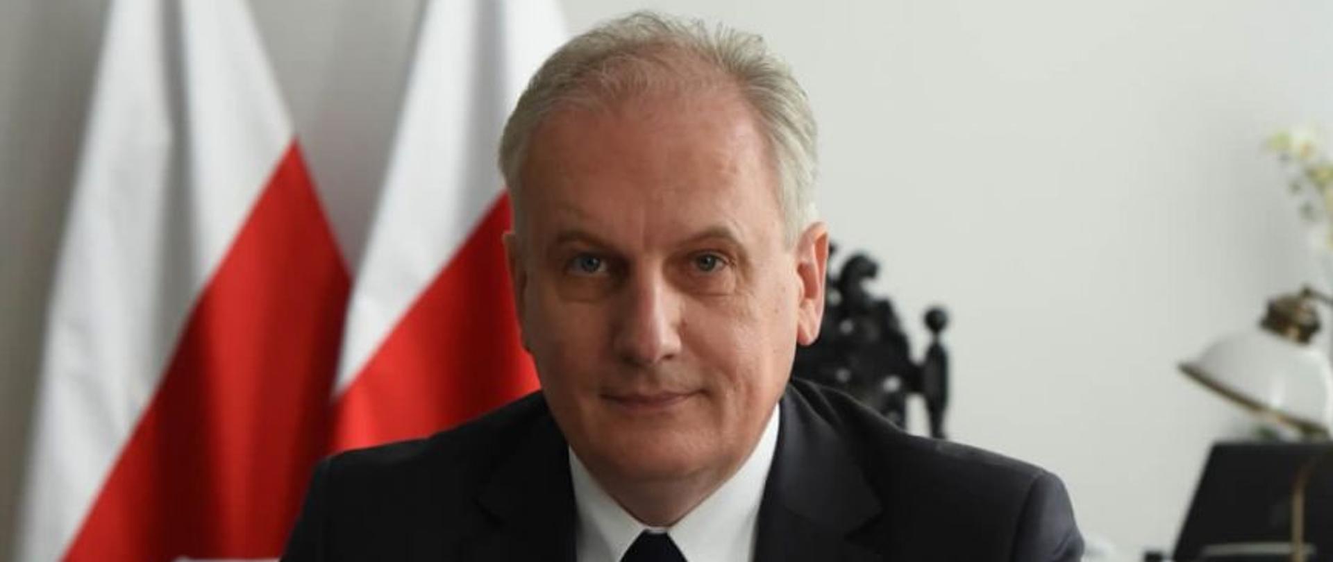 Wojewoda pomorski Dariusz Drelich na tle flagi i godła Polski