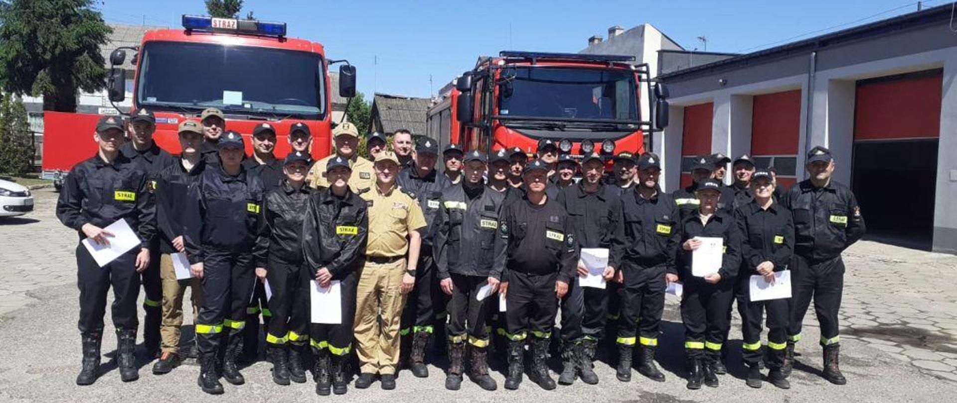 Widać uczestników kursu na tle samochodów pożarniczych.