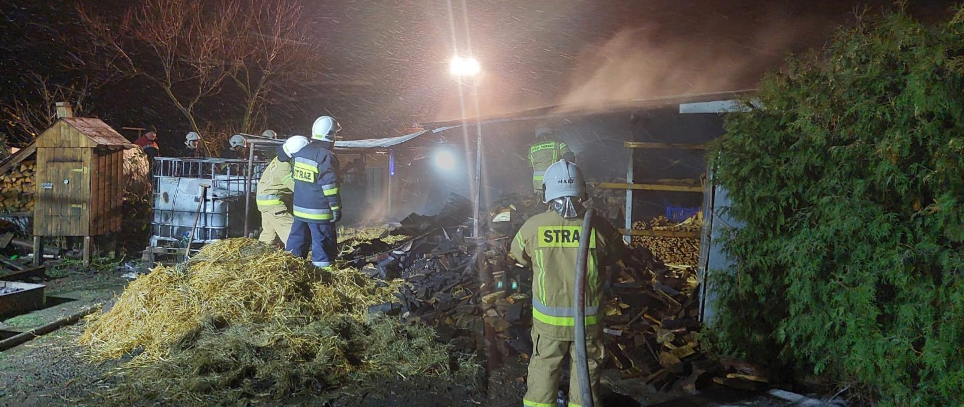 Widać kilku strażaków podczas gaszeniu pożaru, jest noc