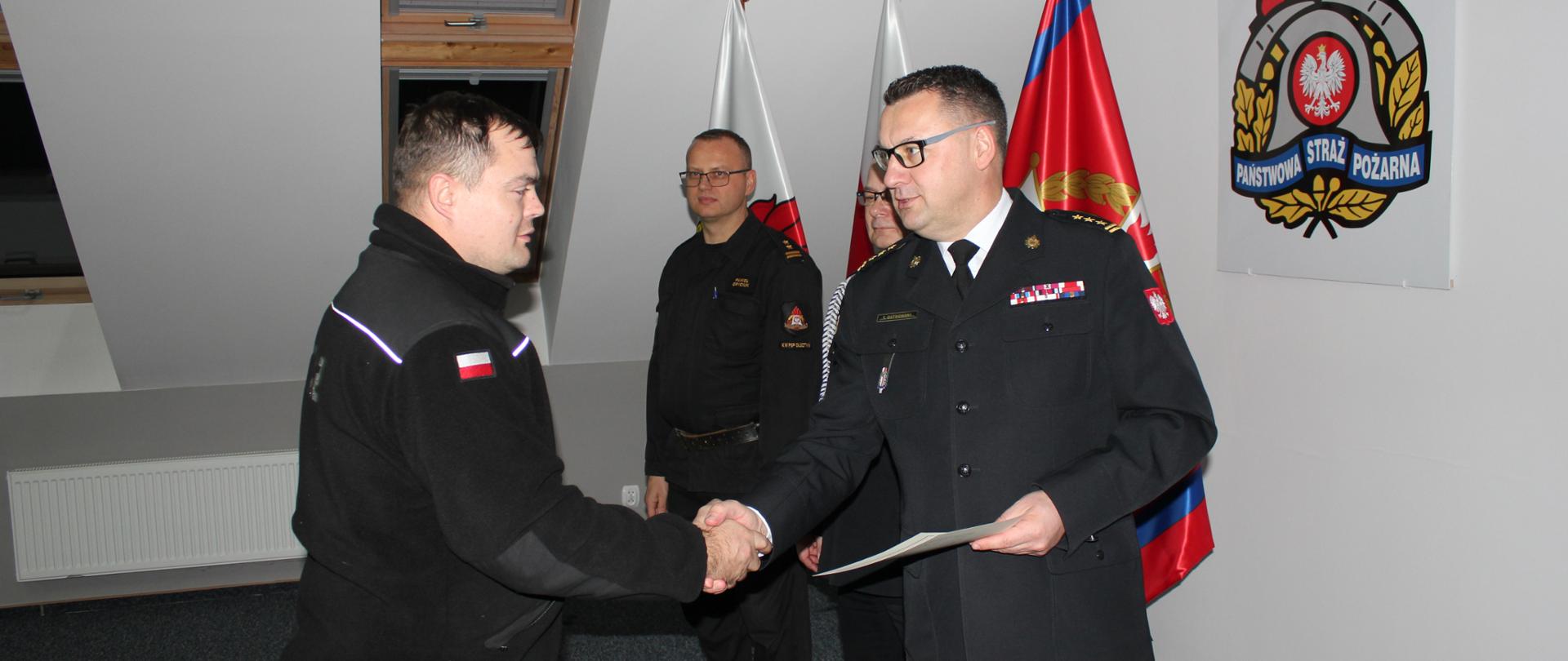 Zastępca Komendanta Wojewódzkiego PSP wręcza zaświadczenie potwierdzające uzyskane kwalifikacje. 