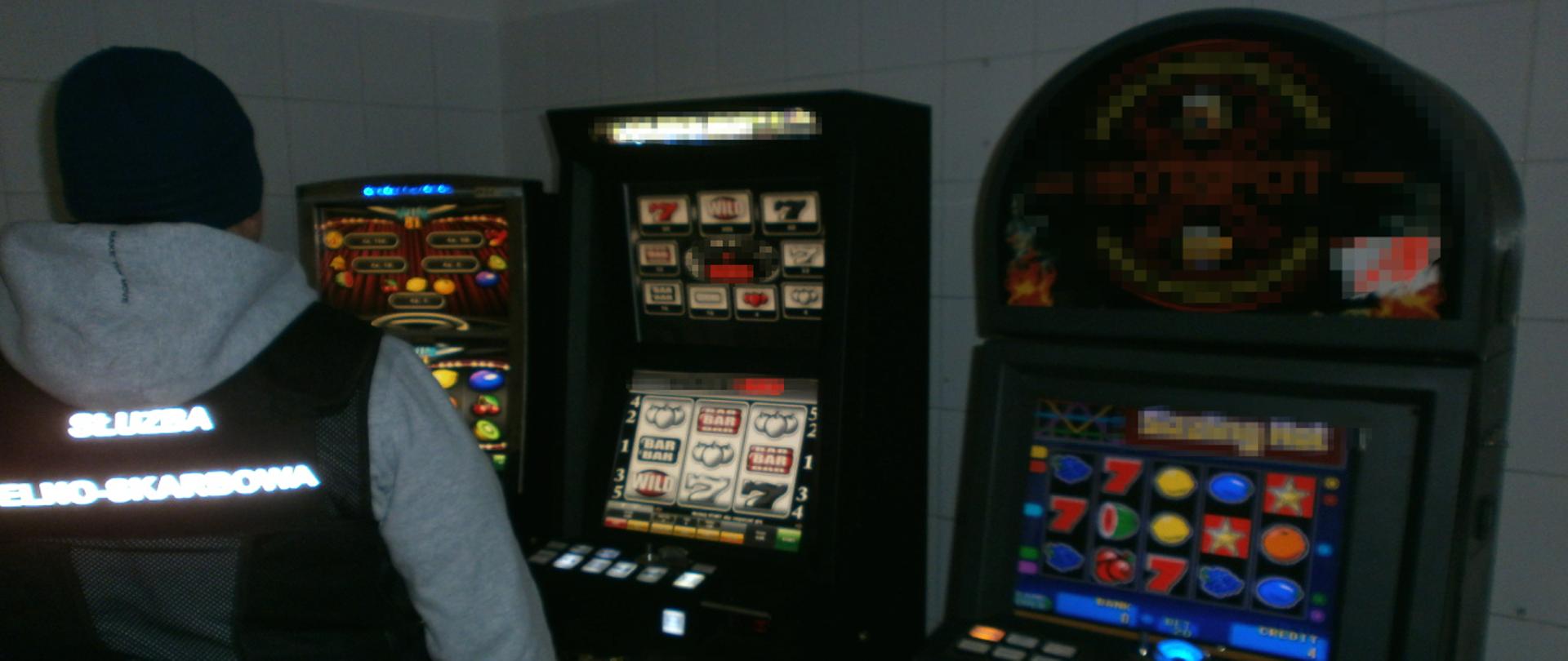 Funkcjonariusz Służby Celno-Skarbowej stojący obok ujawnionych nielegalnych automatów do gier hazardowych.