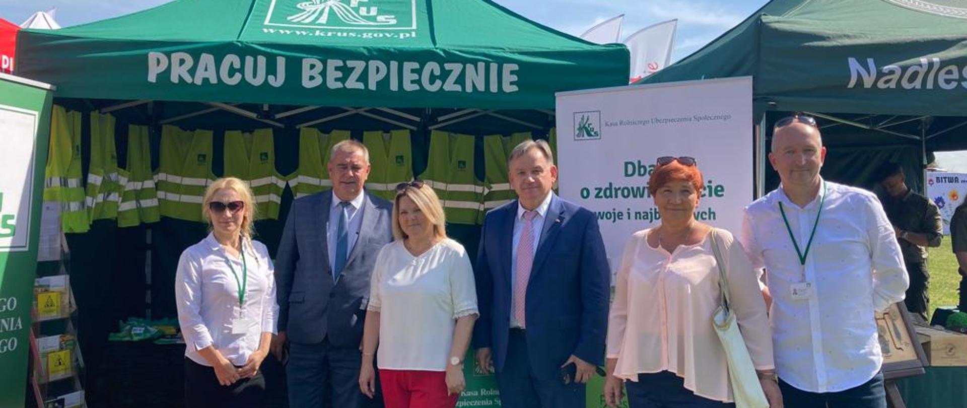 grupa osób stojących na tle stoiska informacyjnego