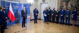 Ambasador Lang stoi przed mikrofonem w towarzystwie grupy dyplomatów. Za nim ścianka z logiem MSZ.