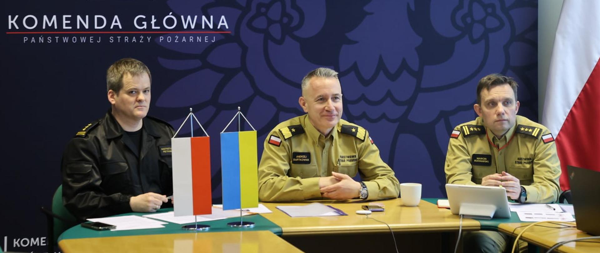 Na zdjęciu widać trzech strażaków podczas wideokonferencji