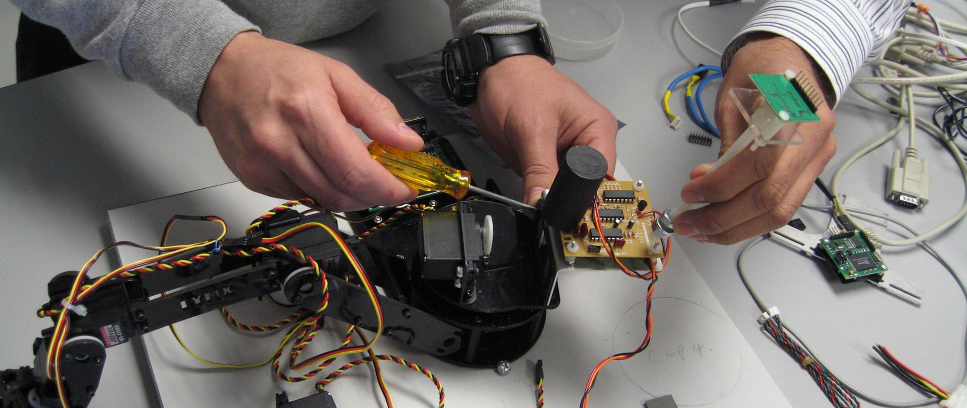 Na zdjęciu widać dwóch mężczyzn pracujących nad jakimś modelem technicznym.