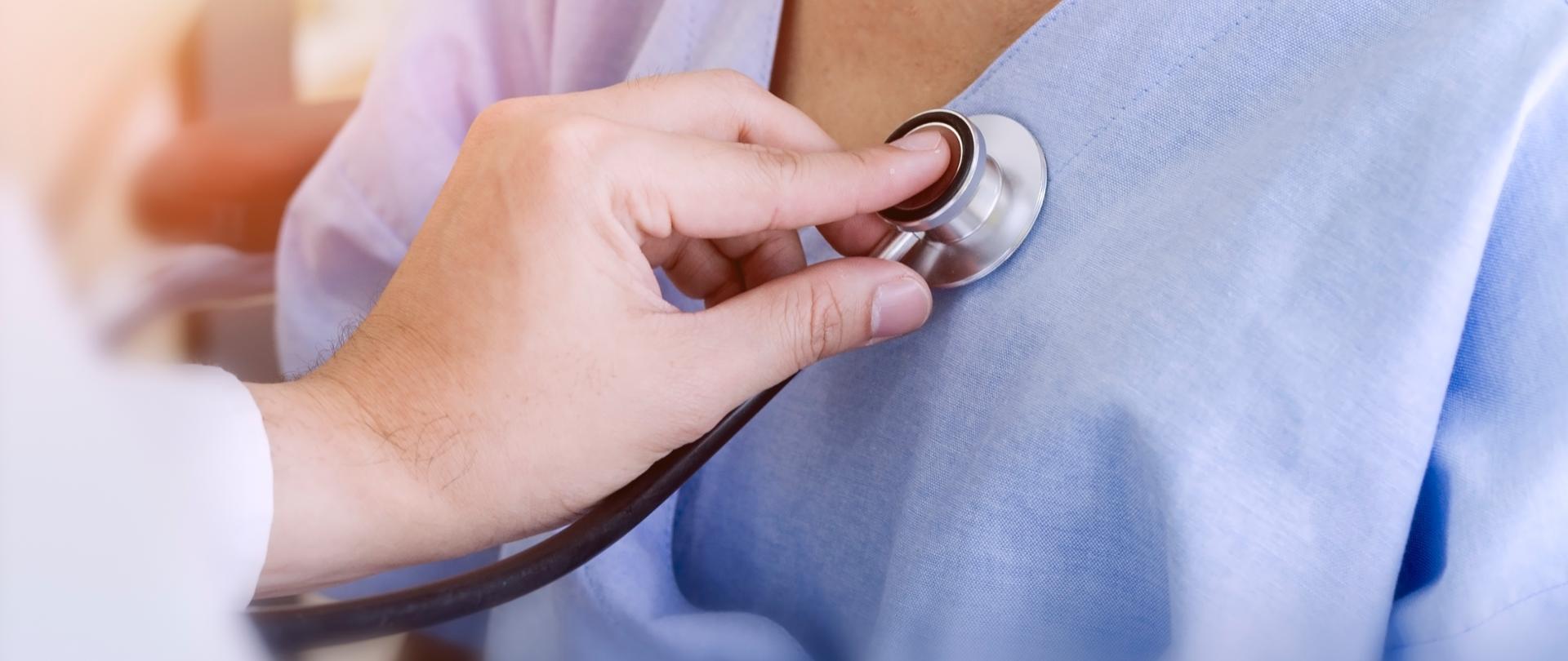 widok ręki lekarza badającego stetoskopem pacjentkę