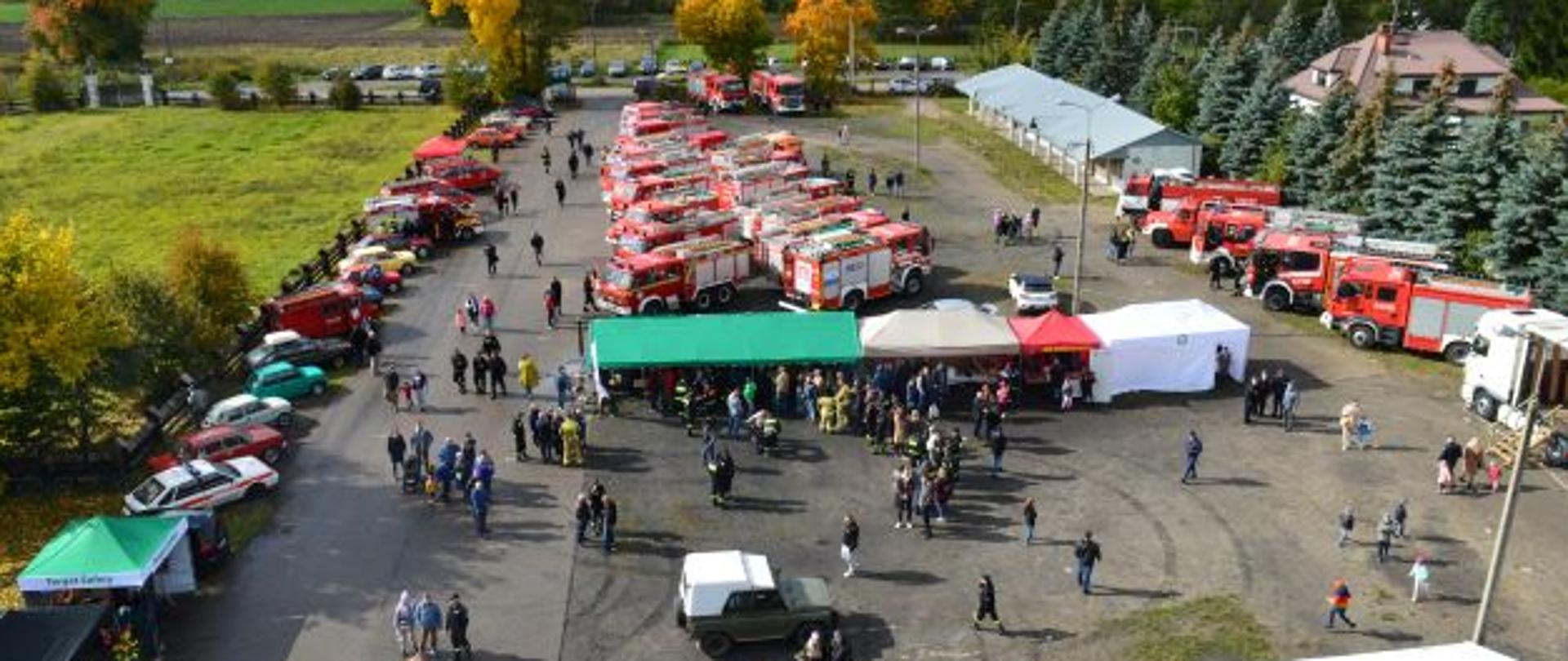 Widok z góry na targowisko w Stanisławowie, na którym ustawione są pojazdy pożarnicze oraz stoiska podczas zlotu 