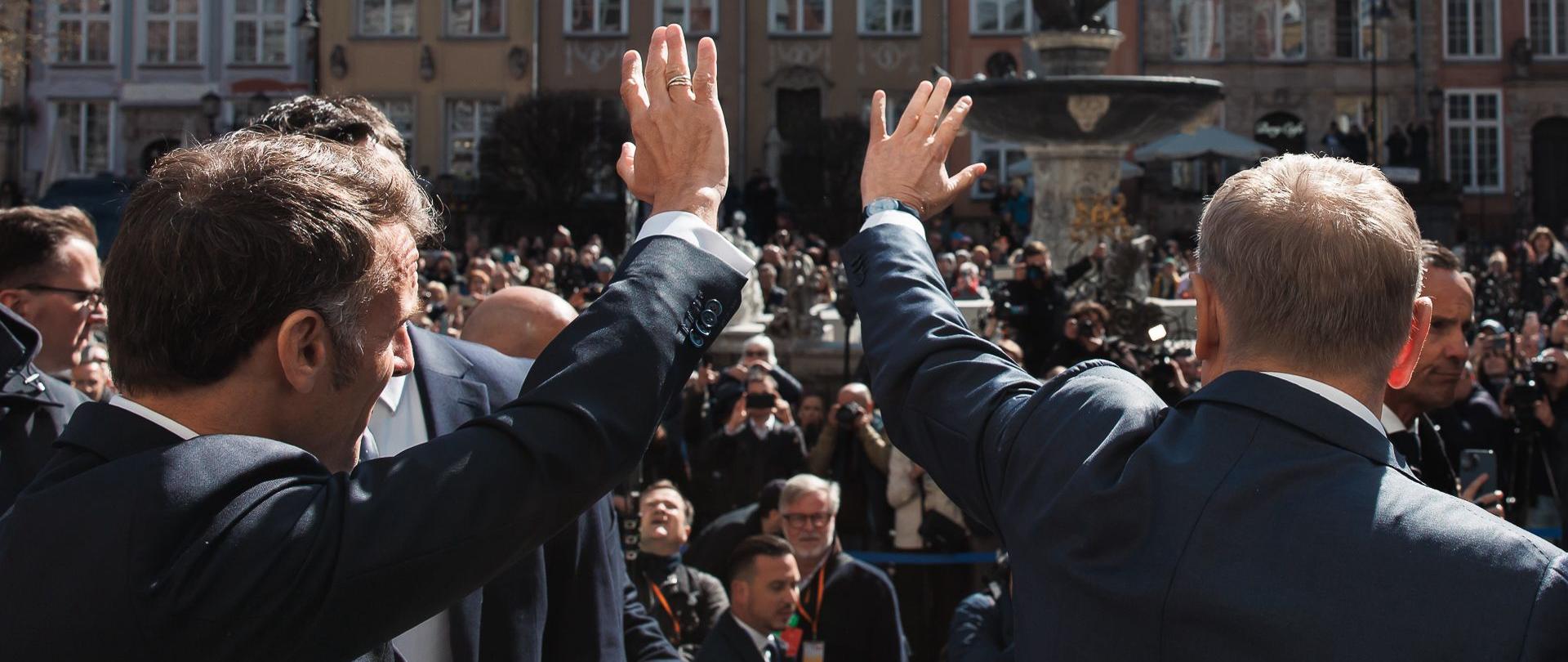 dwóch mężczyzn macha do tłumu zgromadzonego przed fontanna Neptuna w Gdańsku, 20.04.2025 r. 