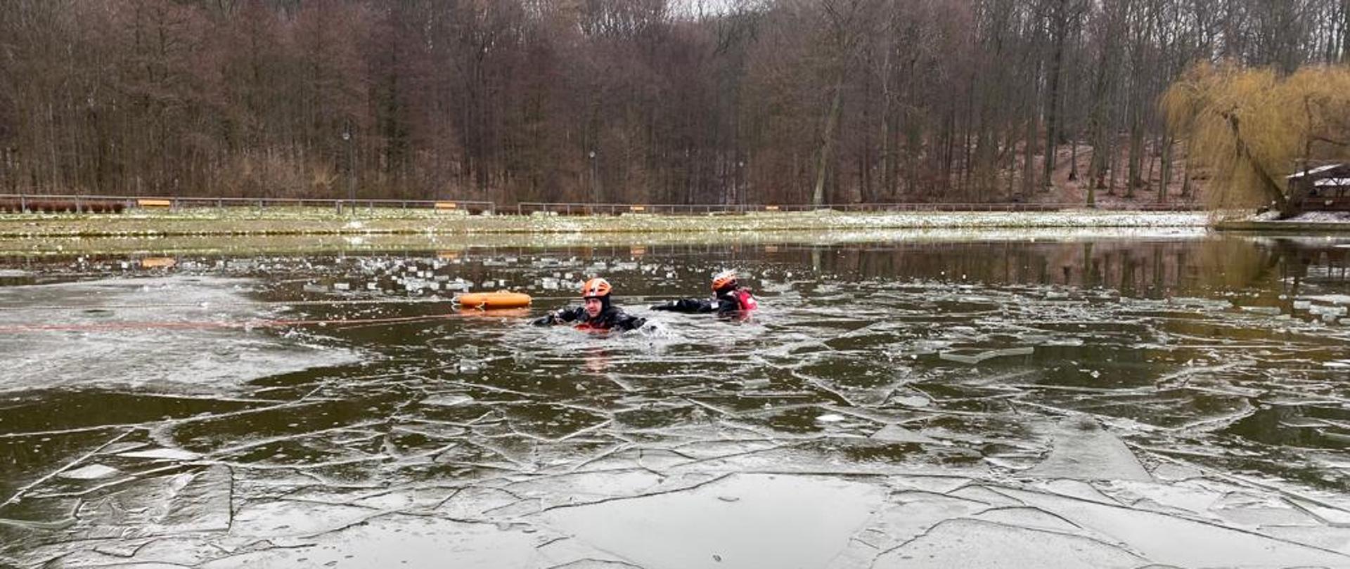 Strażak ubrany w skafander zanurzony w wodzie pokrytej cienką warstwą lodu