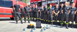 Na zdjęciu strażacy wchodzący w skład grupy ratownictwa chemicznego Płock 6 na tle samochodu ratownictwa chemicznego.
