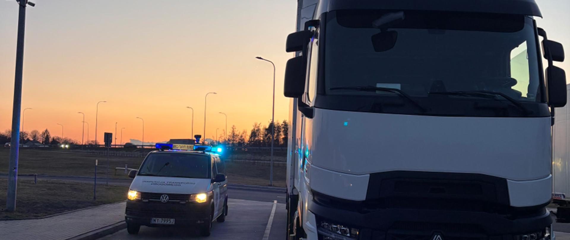 Kontrola drogowa: ciężarówka i pojazd inspekcji z migającymi światłami na tle pomarańczowej łuny zachodu słońca