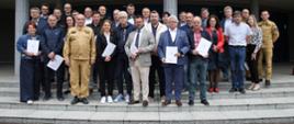 Pamiątkowe zdjęcie grupowe uczestników szkolenia z zakresu ochrony ludności i obrony cywilnej dla osób pełniących funkcję wójtów, burmistrzów i prezydentów miast (27 osób) w towarzystwie Komendanta Centralnej Szkoły PSP, kobiety oraz dwóch oficerów CS PSP