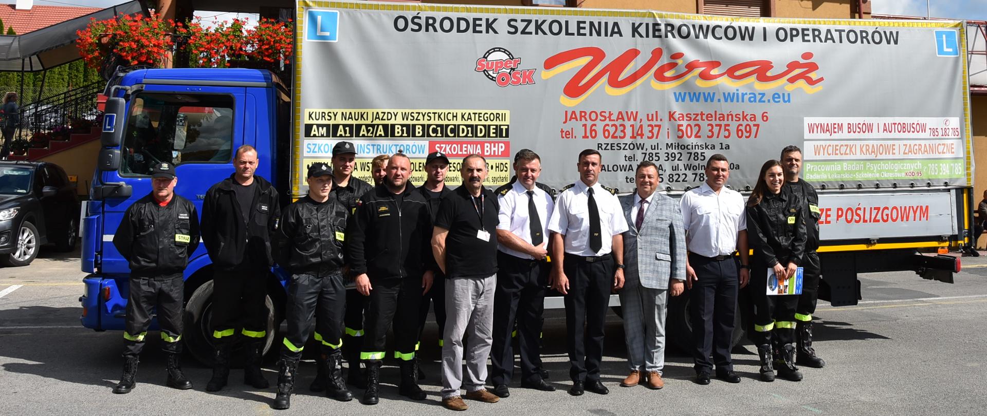 Na zdjęciu widać strażaków oraz prezes ośrodka szkolenia "Wiraż", pozujących przed ciężarówką z reklamą firmy.