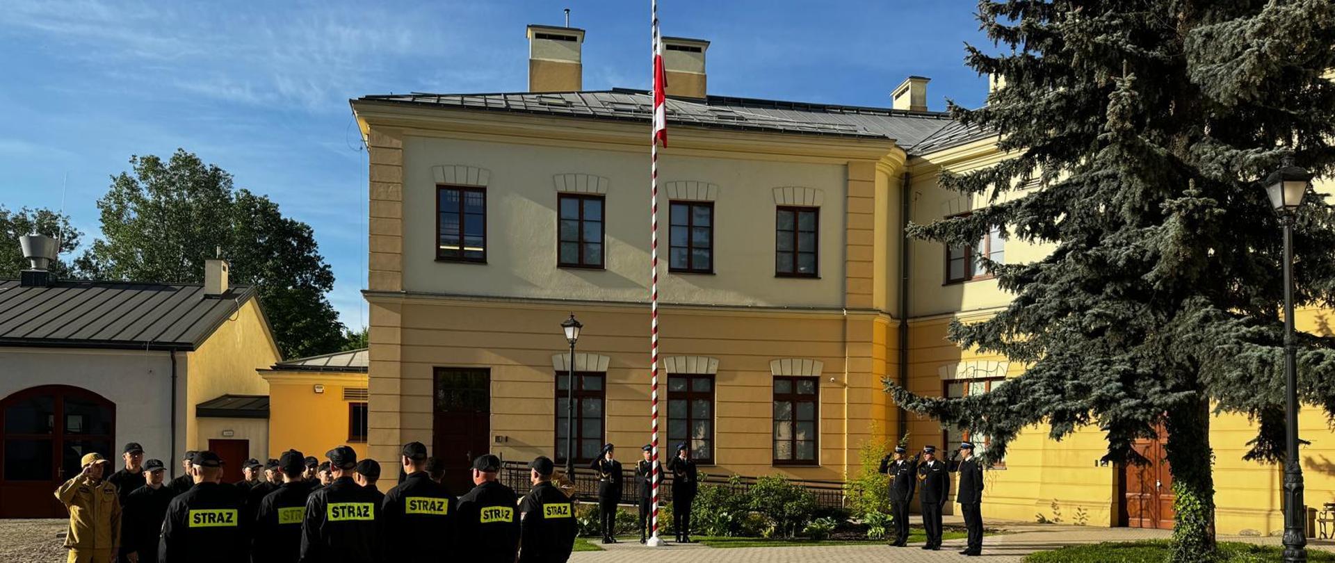 Na zdjęciu widoczni strażacy podczas uroczystej zbiórki przed koszarami z okazji Dnia Flagi RP