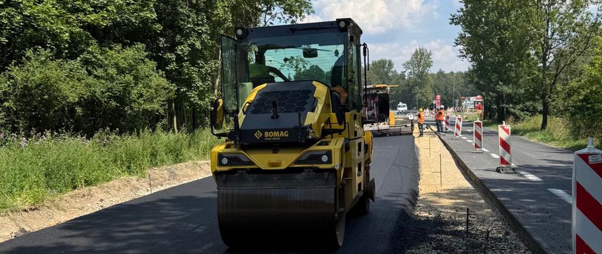 Na zdjęciu widzimy walec budowlany, trwa asfaltowanie nawierzchni jezdni. 